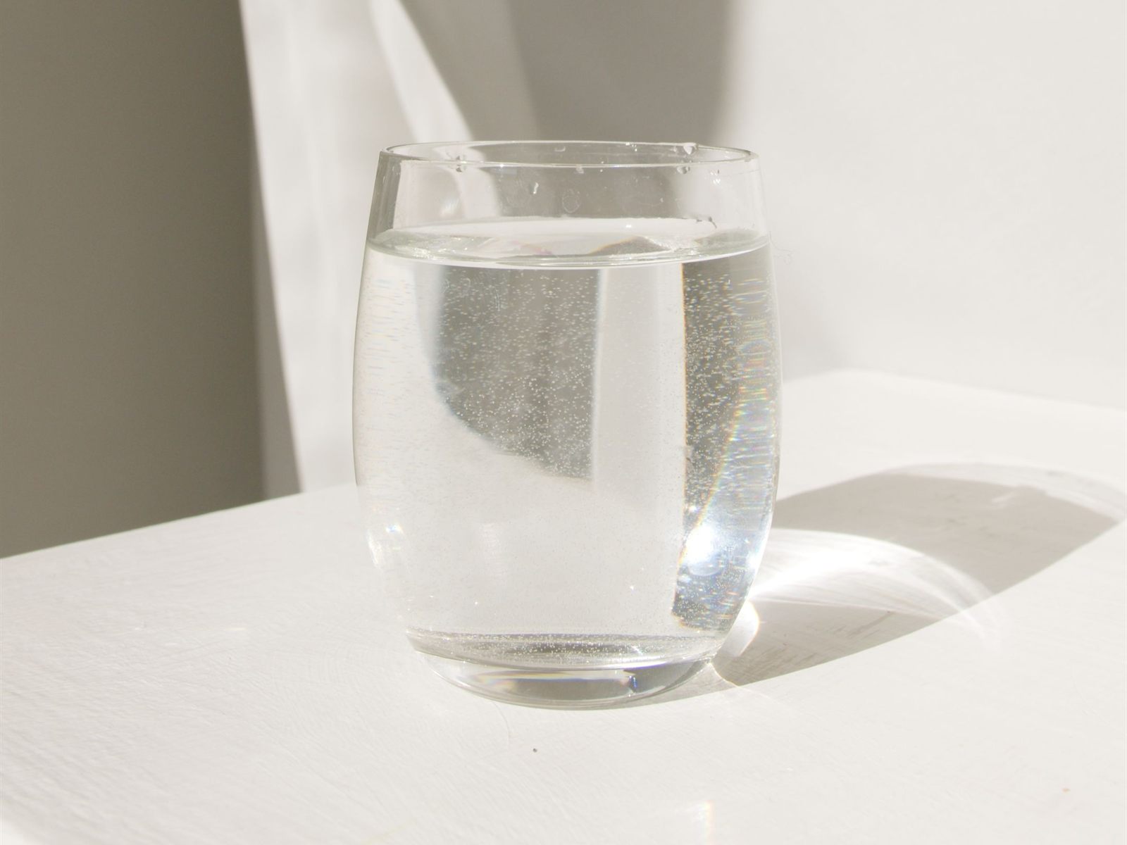 A clear glass of water on a sunlit windowsill