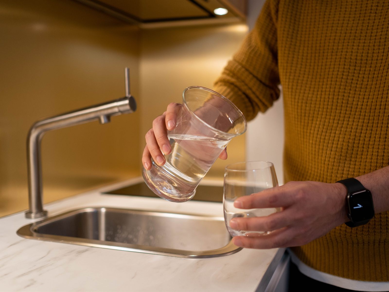 Pouring a glass of water at a modern kitchen sink