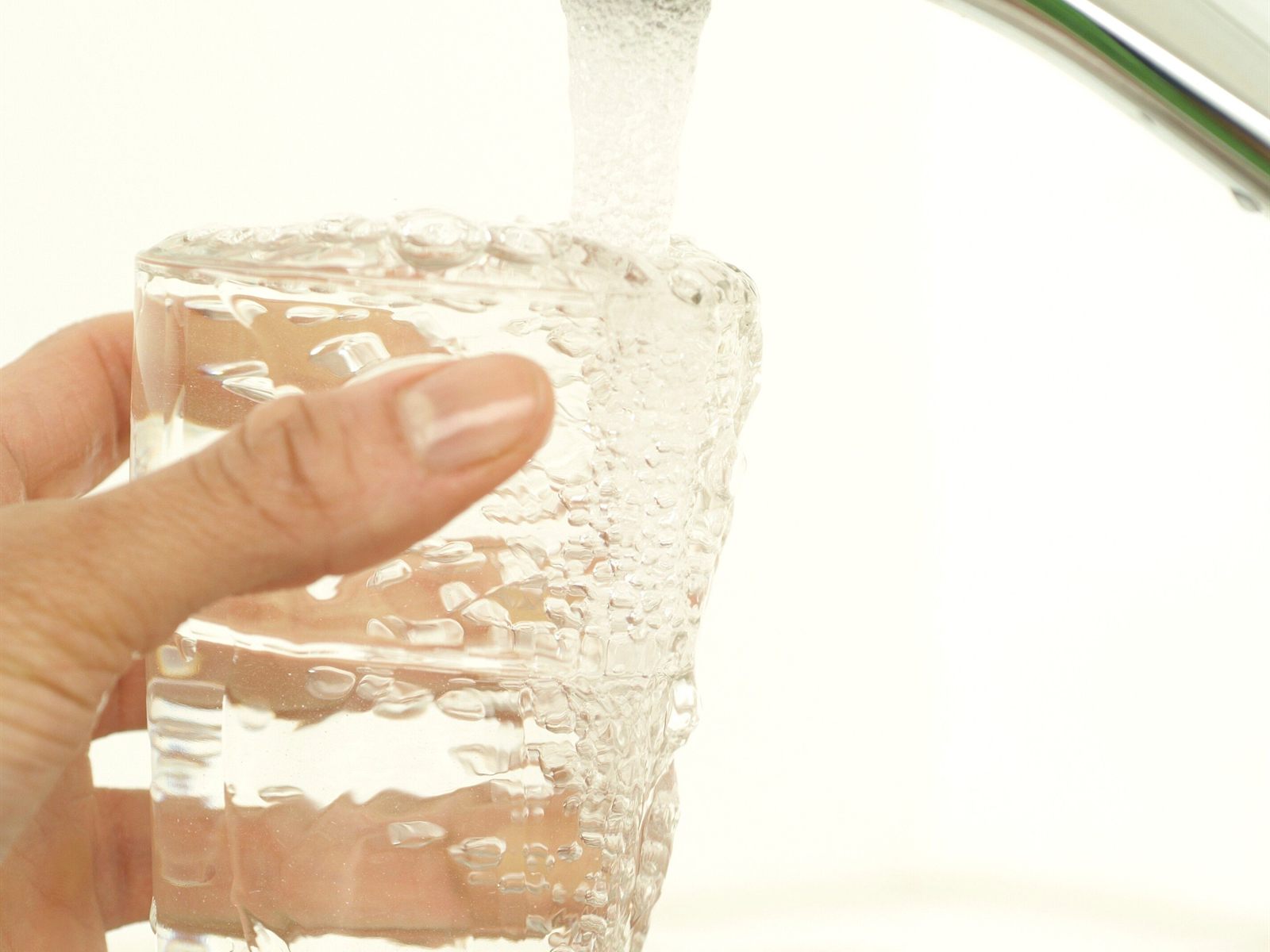 Filling a glass with clear water from a chrome kitchen faucet