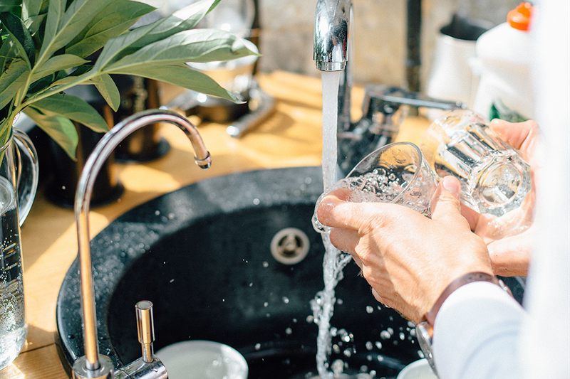 Rinsing a drinking glass spot-free under a kitchen faucet